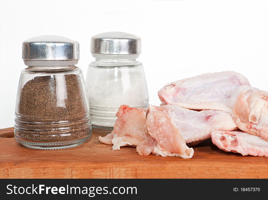 Raw chicken on plate with salt and pepper