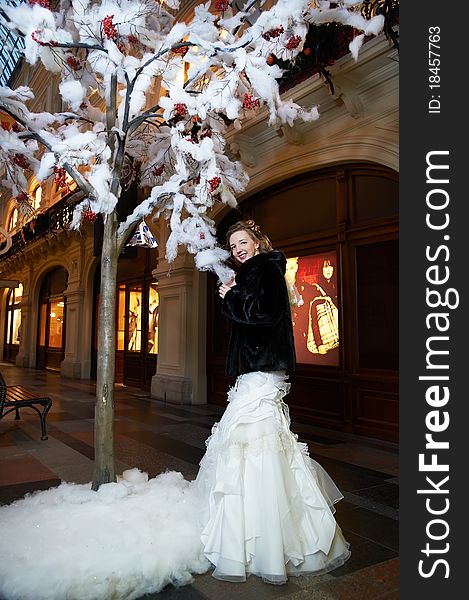 Beauty bride near artifical tree in big shop at wedding day