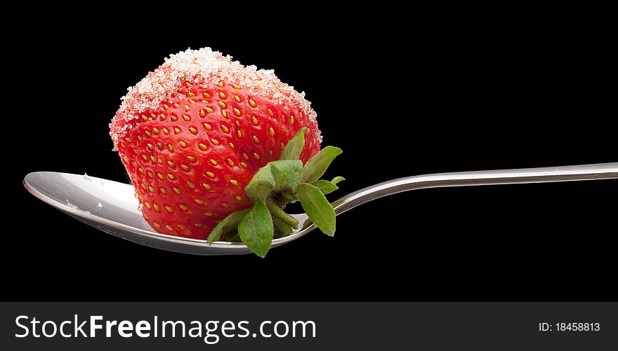 Ripe strawberries with sugar on the spoon on black