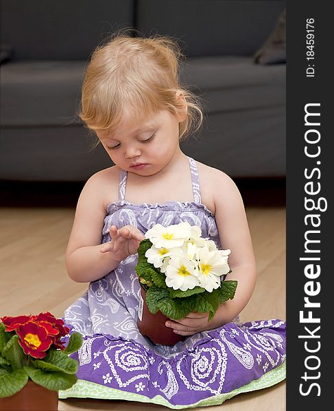 Girl sits on the floor and holds flowers in pots in her hands. Girl sits on the floor and holds flowers in pots in her hands