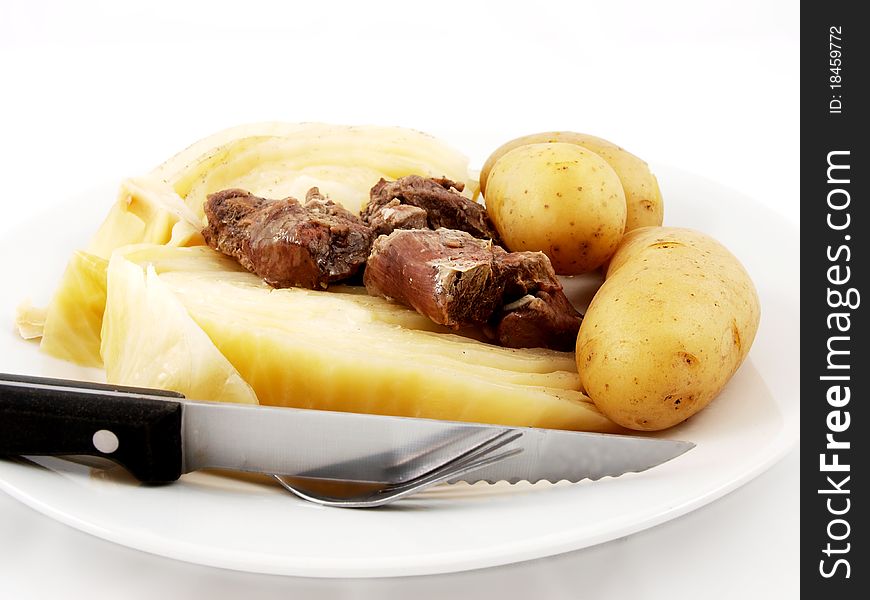 Mutton with cabbage, knife and  fork on white plate towards white background