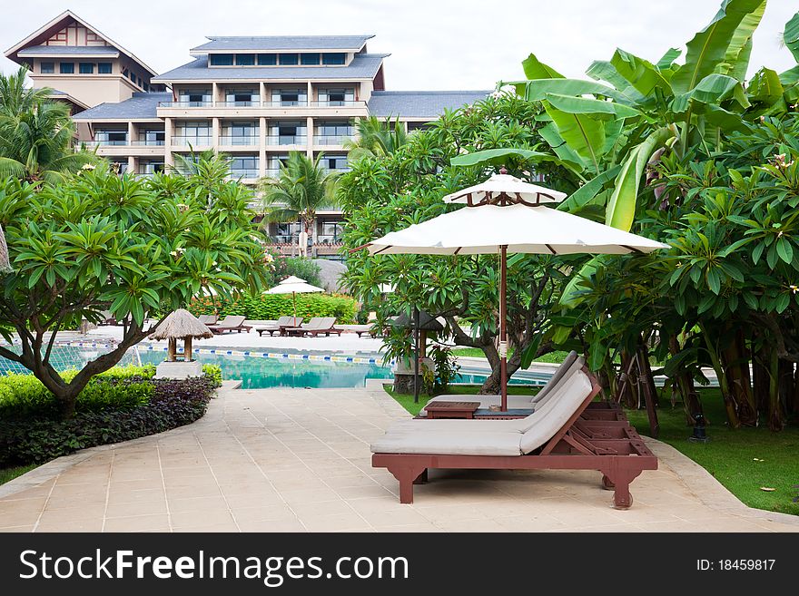 Hotel garden with swiiming pool and relaxing chairs at poolside.