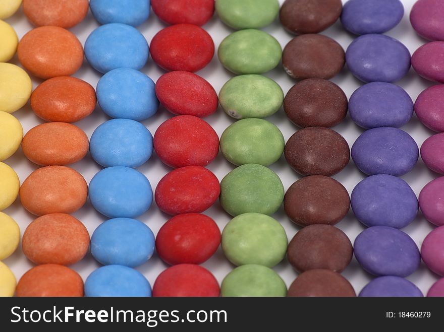 Small round candy placed on a white surface in a line pattern mode. Small round candy placed on a white surface in a line pattern mode.