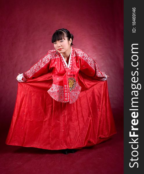 Elegant chinese model in traditional red dress on the red background.