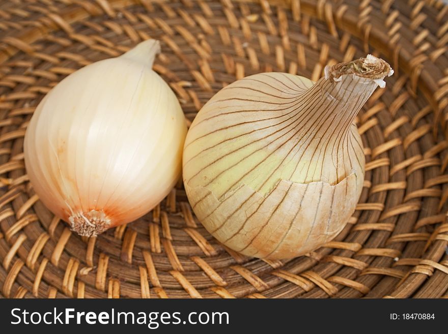 Ripe onions on a wicker plate isolated on white background
