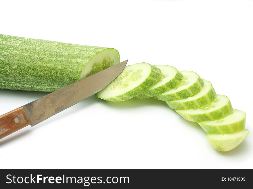 Cucumber slices with small knife on white background.