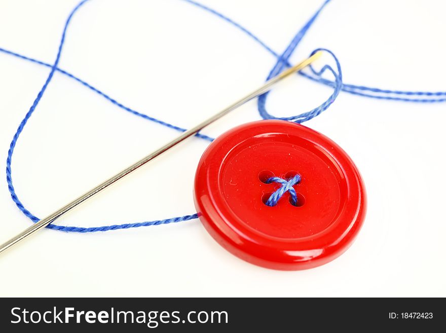 Button with needle and thread isolated on white background