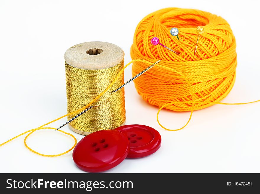 Colored thread, needles and buttons on a white background