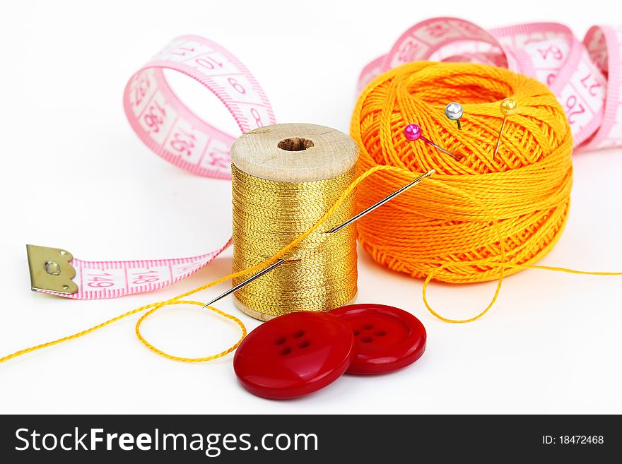 Colored thread, needles and buttons on a white background