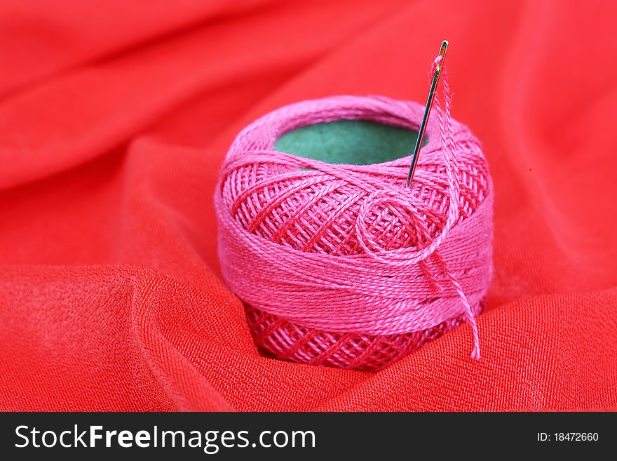 Thread and needle on a red background. Thread and needle on a red background