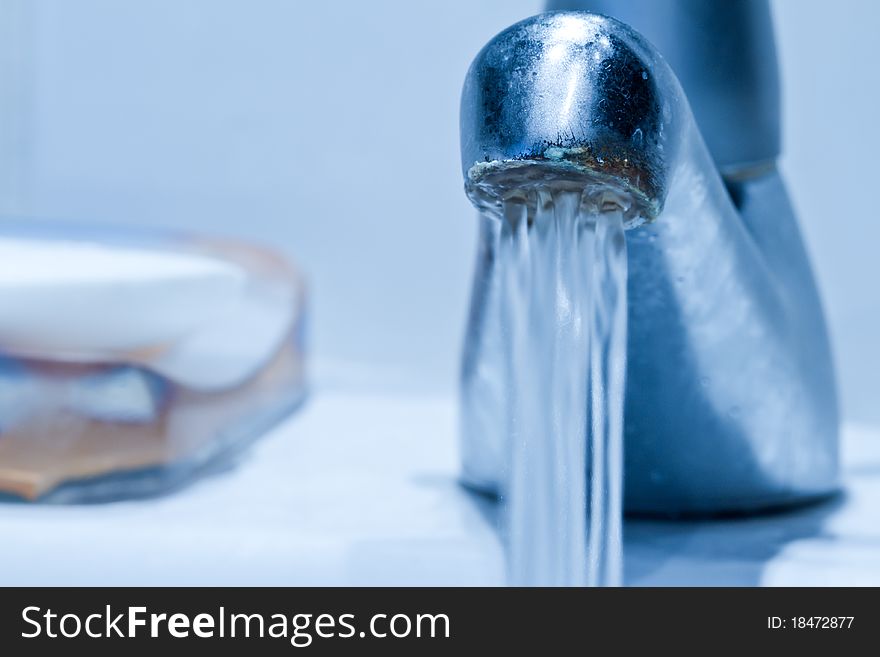 Cool toned and desaturated flowing faucet with shallow focus. Cool toned and desaturated flowing faucet with shallow focus.