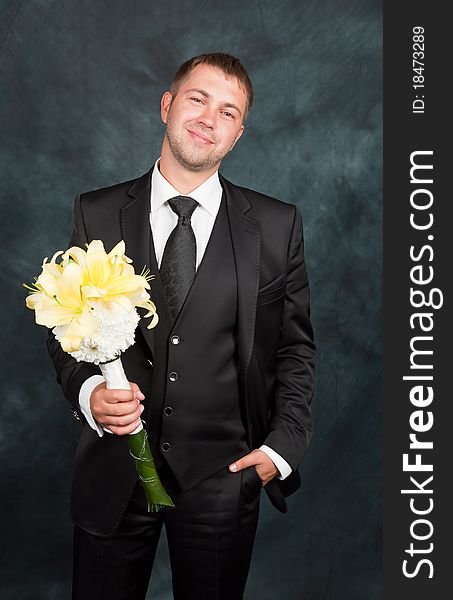 A young groom with a bouquet in studio