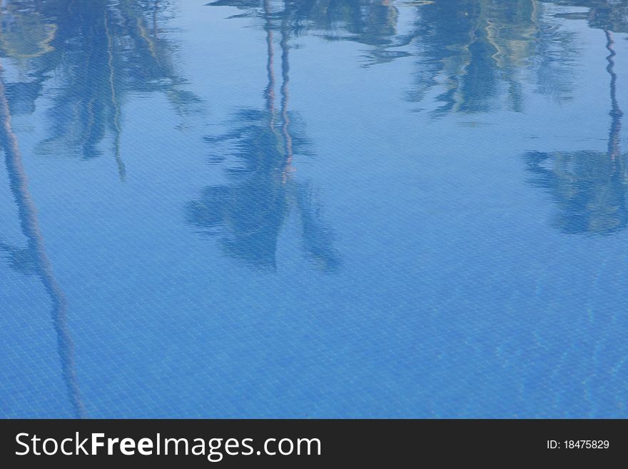 Background made of blue water with reflected palm trees