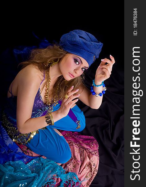 Beautiful girl in a turban and a stylized ethnic costume sits on headscarves