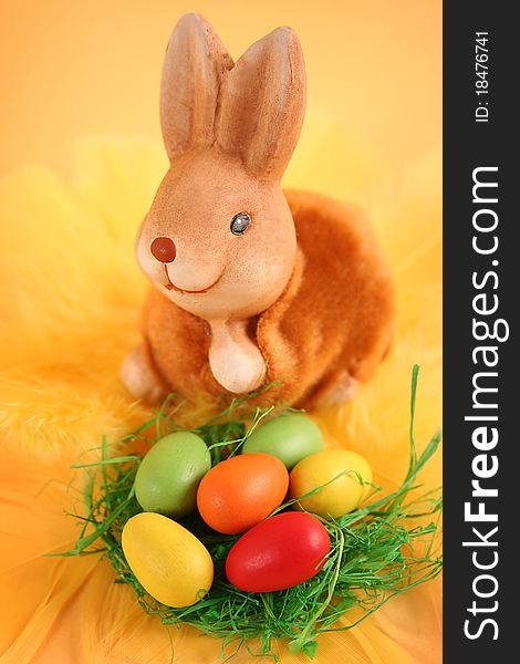 Easter bunny with colored eggs on yellow background