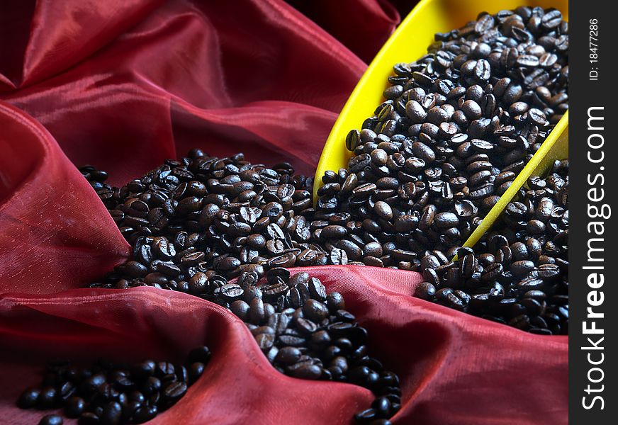 The image shows a part of a blade filled with coffee beans over a red shawl