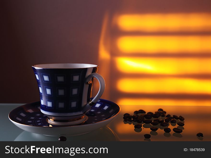 Cup and coffee beans on a glass table.