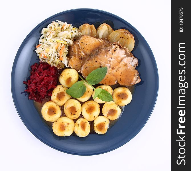 Pork steak and dumplings with side salads and baked onions, decorated with a mint twig, on a white background