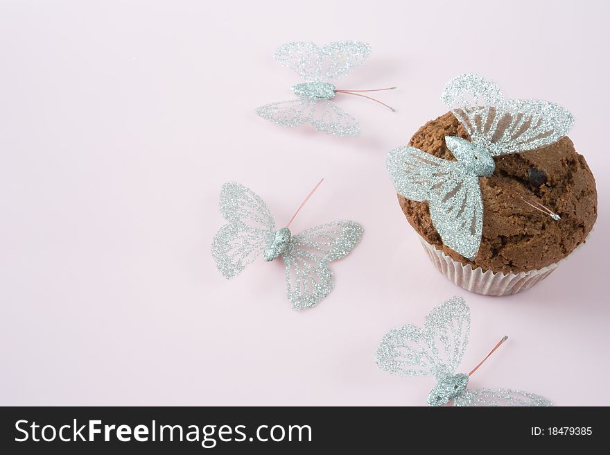 Chocolate muffin on a pink background with butterflies. Chocolate muffin on a pink background with butterflies