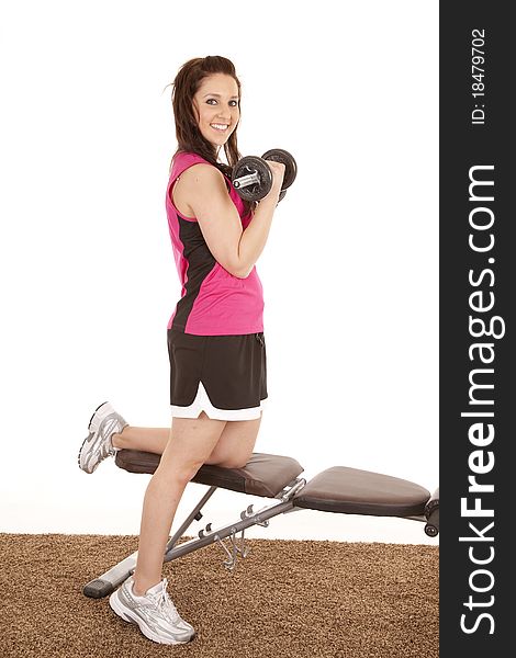 A woman in a pink tank top is curling some weights. A woman in a pink tank top is curling some weights.