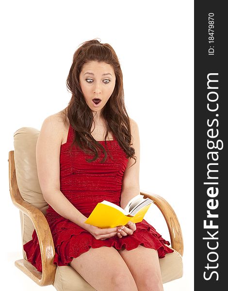 A woman in a red dress is reading a book and looks shocked. A woman in a red dress is reading a book and looks shocked.