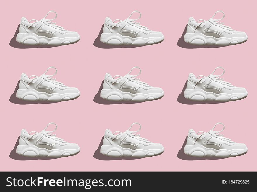 Regular seamless pattern of light sneakers with a hard shadow on a pink background. Photo collage. Fashion blog, sport lifestyle. Printing on fabric, wrapping paper