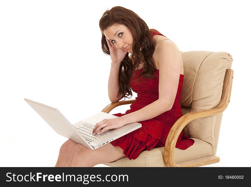 A woman with a laptop is wearing a red dress sitting in a chair. A woman with a laptop is wearing a red dress sitting in a chair.