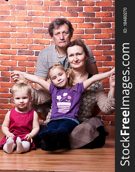 Happy seniors couple with grandchildren against brick wall