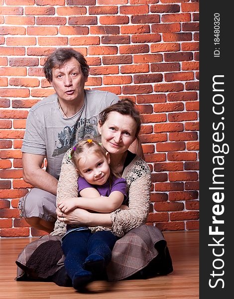 Happy seniors couple with grandchild against brick wall