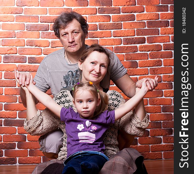 Happy seniors couple with grandchild against brick wall