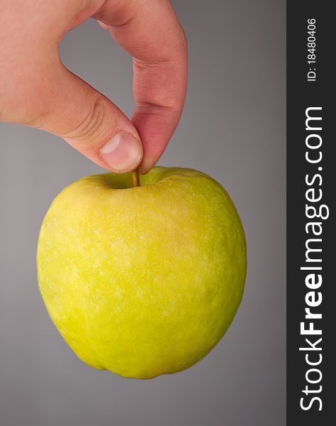 Green apple in a hand on a grey background