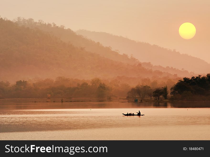 Silhouette of a fisherman in a boat on a lake in the morning