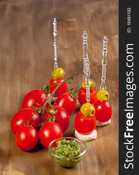 Snacks with green olives with mozzarella cheese and fresh tomato on wooden table. Snacks with green olives with mozzarella cheese and fresh tomato on wooden table