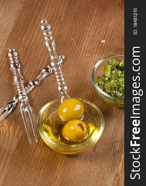 Snacks with green olives and pesto sauce in little glass bowls