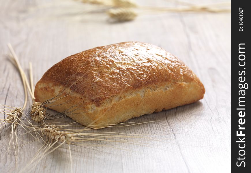 A close up of a baked bread on a wooden surface. A close up of a baked bread on a wooden surface