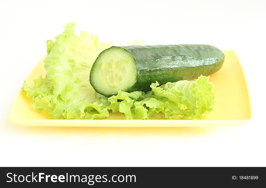 A green cucumber on the salad leaf on the white background