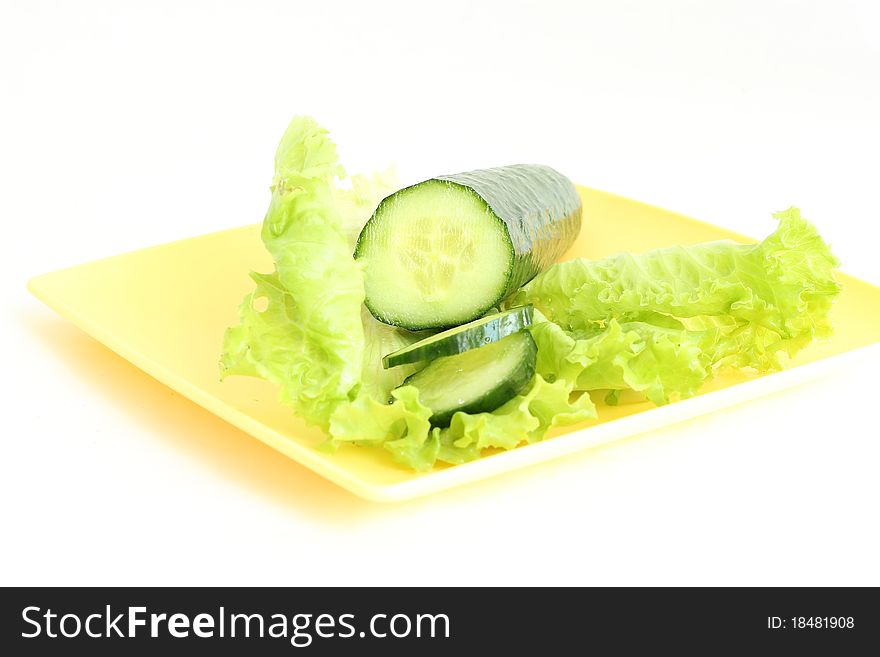 A green cucumber on the salad leaf on the white background