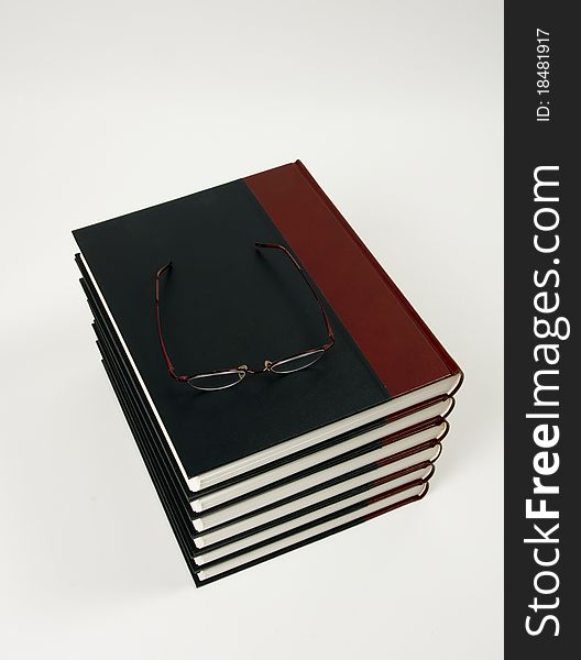 Close-up of stacked books with eyeglasses up on a light background. Close-up of stacked books with eyeglasses up on a light background