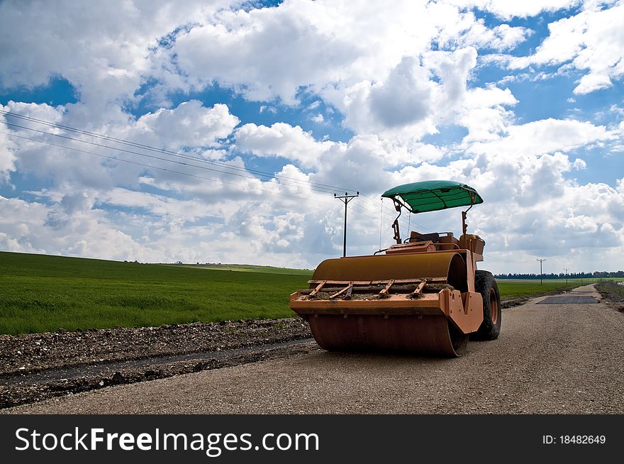 Orange tractor on a background of grass and sky