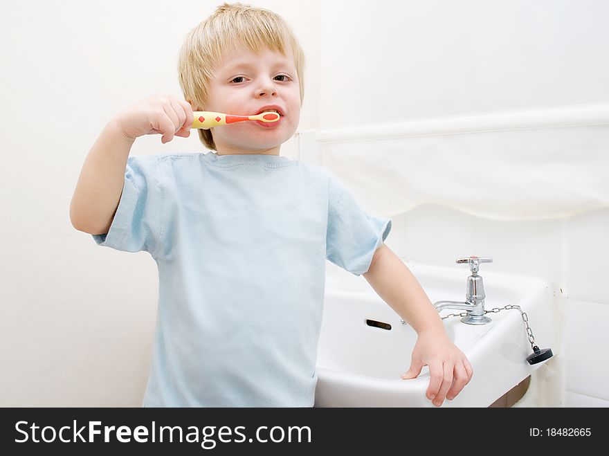 A toddler brushing his teeth in the bathroom at bedtime.