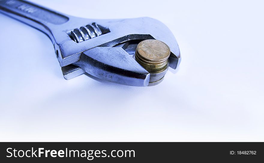 Adjustable wrench gripping a stack of coins with shallow depth of field. Adjustable wrench gripping a stack of coins with shallow depth of field.