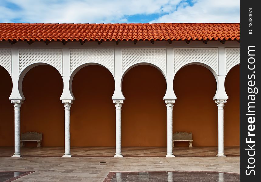 Pattern of a modern covered arcade with the tile roof on blue sky background.It is stylized to classical Spanish style. Caesarea, Israel. Pattern of a modern covered arcade with the tile roof on blue sky background.It is stylized to classical Spanish style. Caesarea, Israel.