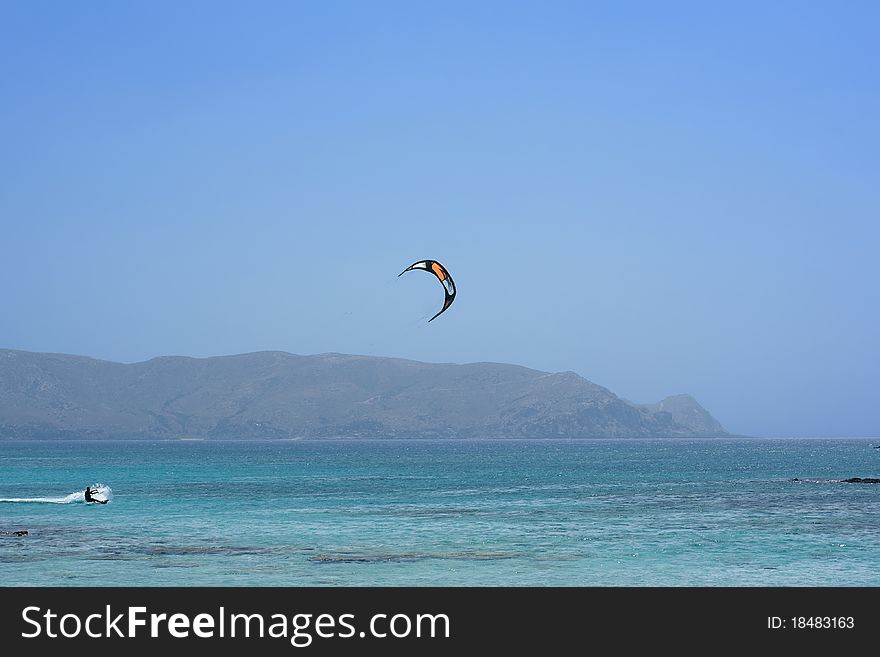 Kite surfer in the blue water surrounded by mountains
