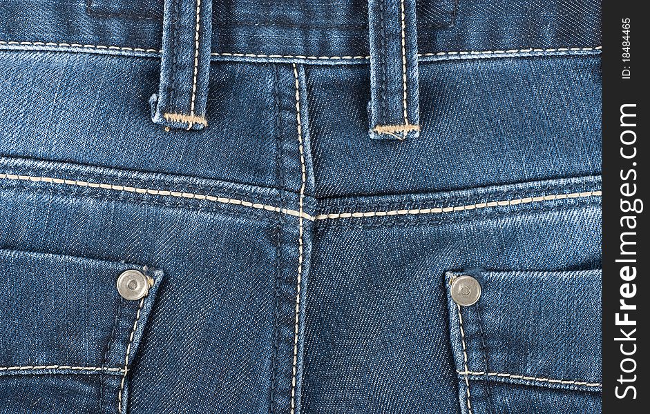 The background of the back pocket of blue jeans. The background of the back pocket of blue jeans