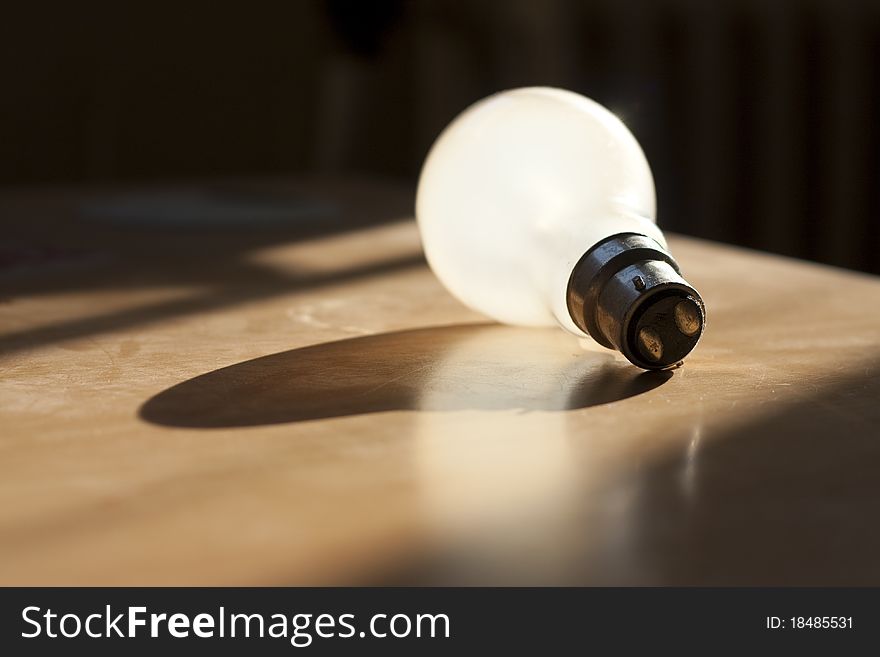 Standard 60w bayonet tungsten lightbulb laying in the sunlight. Standard 60w bayonet tungsten lightbulb laying in the sunlight