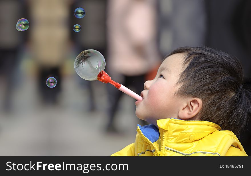 Child blowing soap bubbles in a park