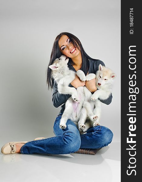 Playing woman with puppies of siberian haski on gray background. Playing woman with puppies of siberian haski on gray background