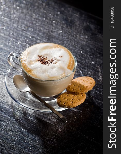 Photo of cappuccino in glass cup on black glass table. Photo of cappuccino in glass cup on black glass table