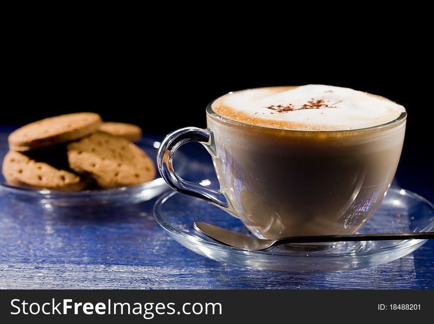 Photo of cappuccino in glass cup on blue glass table. Photo of cappuccino in glass cup on blue glass table