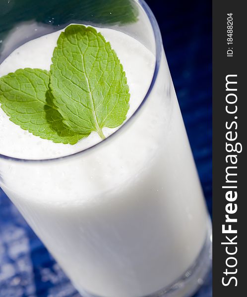 Photo of hot milk in glass with two leaves of green fresh mint. Photo of hot milk in glass with two leaves of green fresh mint